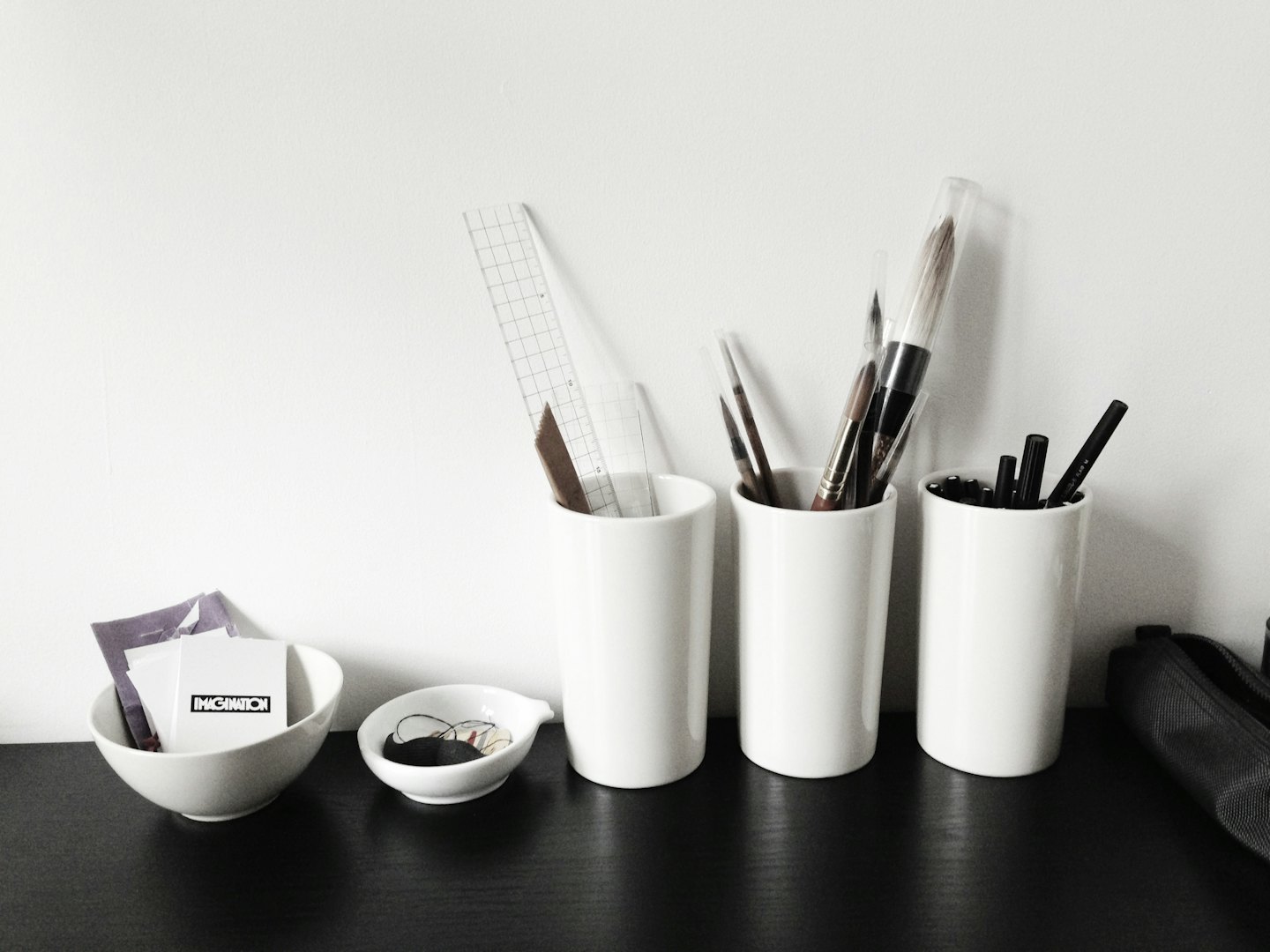Office supplies and brushes organized on a black desk.